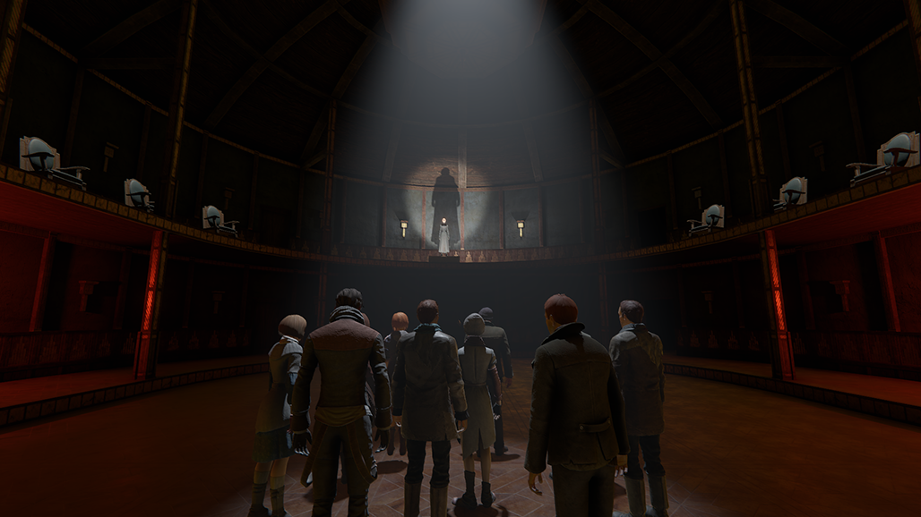 The screenshot is of a dark room that appears to be a council chamber of some kind. A person is standing at the front of the room on a stage with a spotlight on them. There is a group of people standing below, also in a spotlight