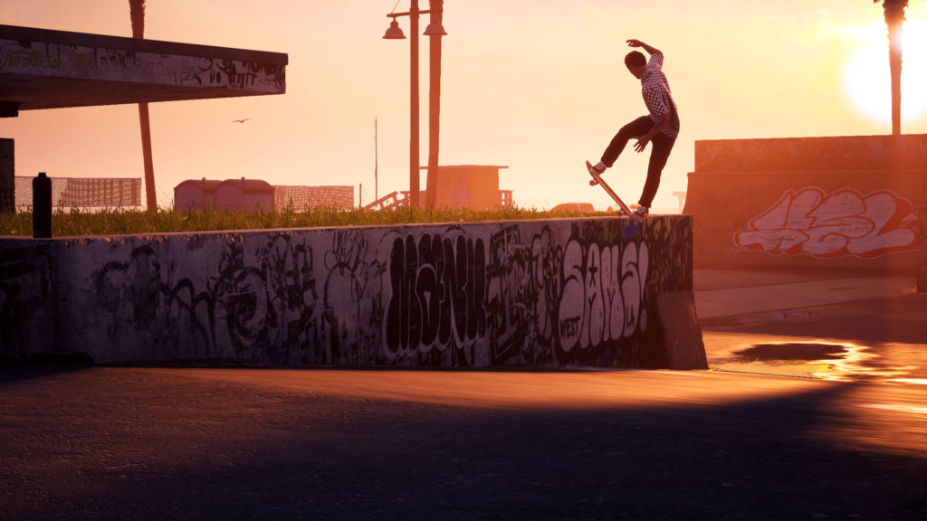 A skater doing a jumping trick over a graffitied wall at sunrise