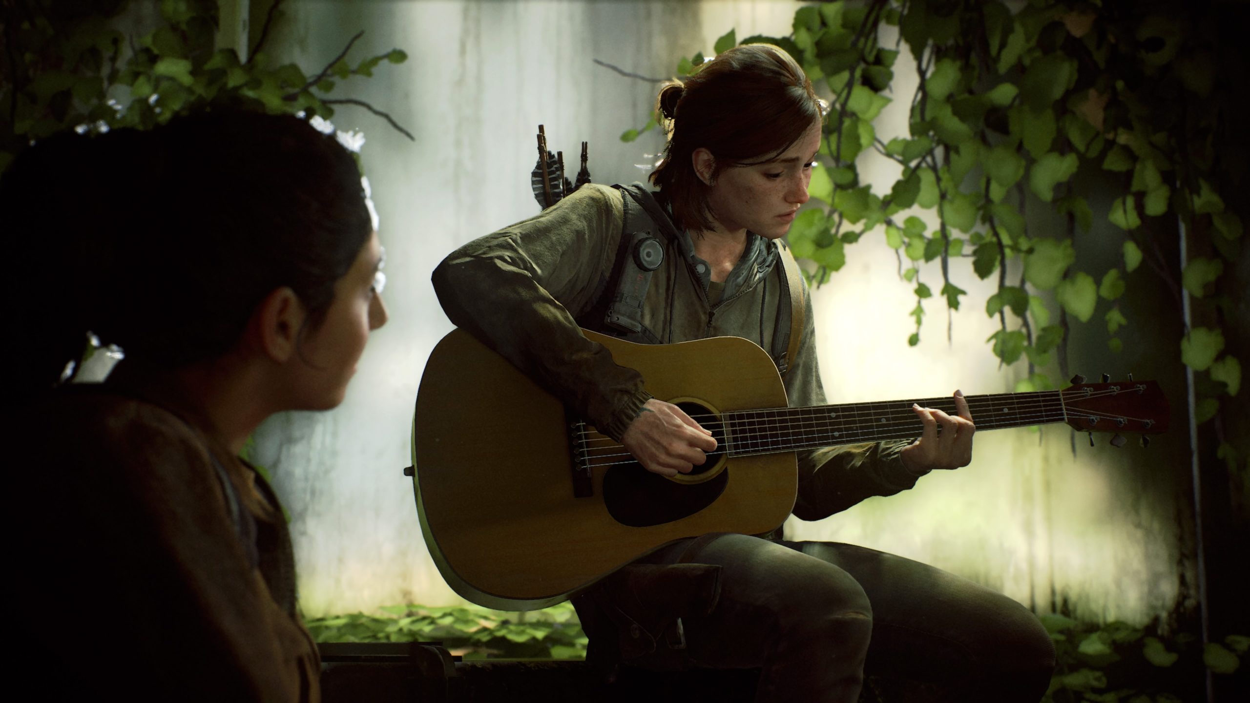Ellie sitting playing a guitar while Dina looks at her from the ground to the left