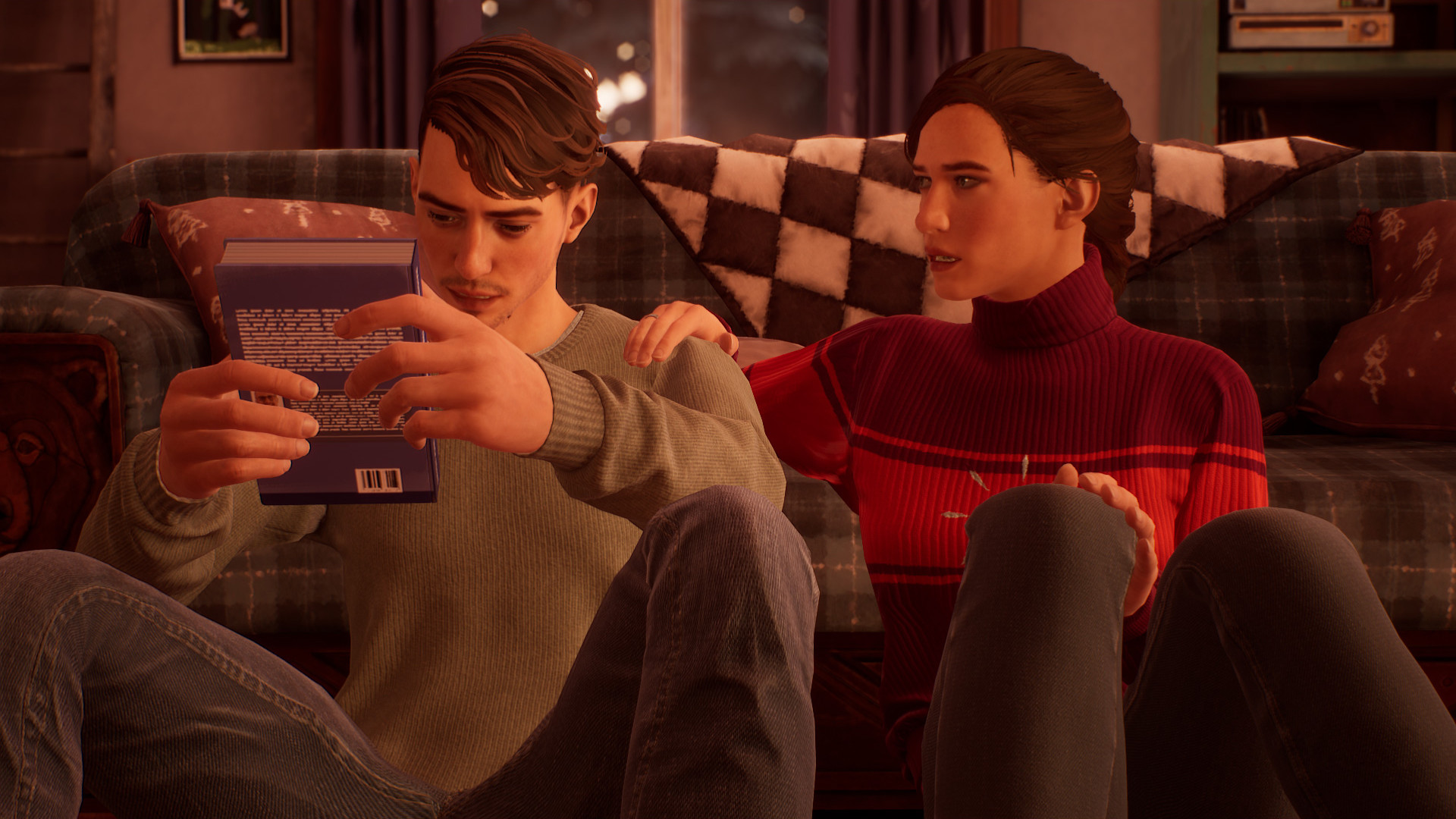 Tyler and his sister both in sweaters and jeans sitting on the floor in front of a couch. Tyler is looking at a book he's holding and his sister has her hand on his shoulder.