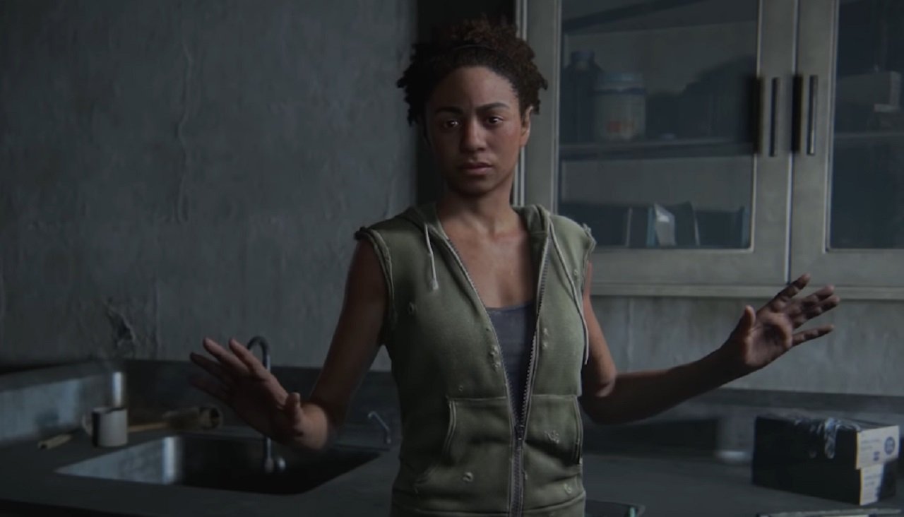 Nora, a black woman probably in her 30s standing in the center of a room holding her hands out to her sides.