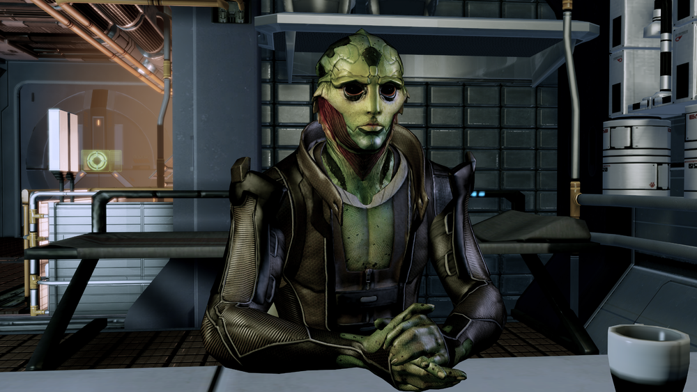 Thane sitting facing the camera with his hands folded on the table in front of him