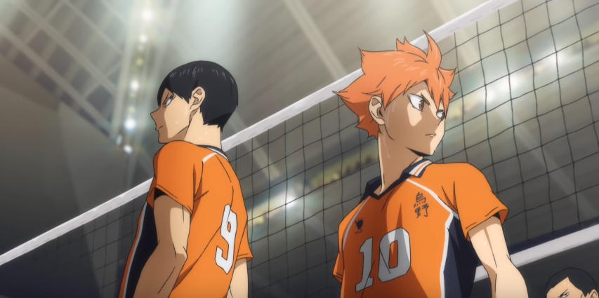 Tobio Kageyama and Shoyo Hinata standing back to back in their orange uniforms with a volleyball net behind them