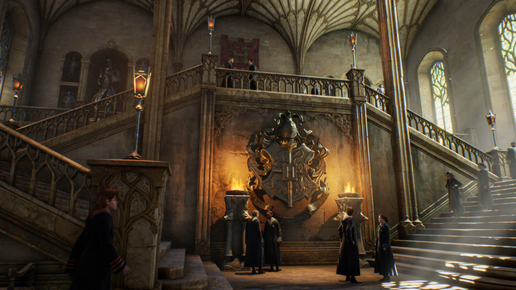 Screenshot from Hogwarts Legacy of students standing on a stairwell under the Hogwarts crest